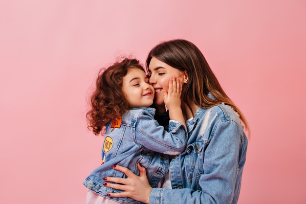 relaxed-preteen-girl-embracing-with-mother-winsome-young-mom-kissing-daughter-pink-background_197531-13683